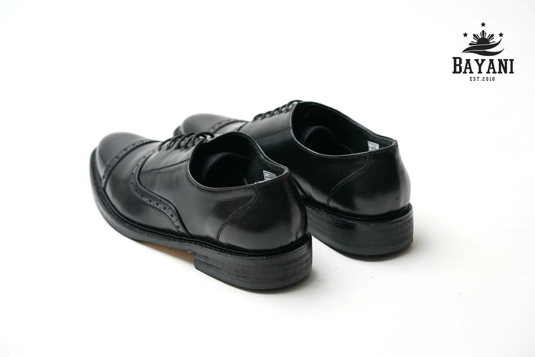 Pair of black dress shoes on a white background with Bayani logo.
