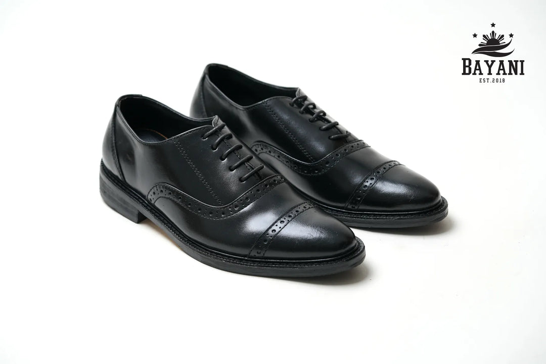 Pair of black dress shoes on a white background with Bayani logo.
