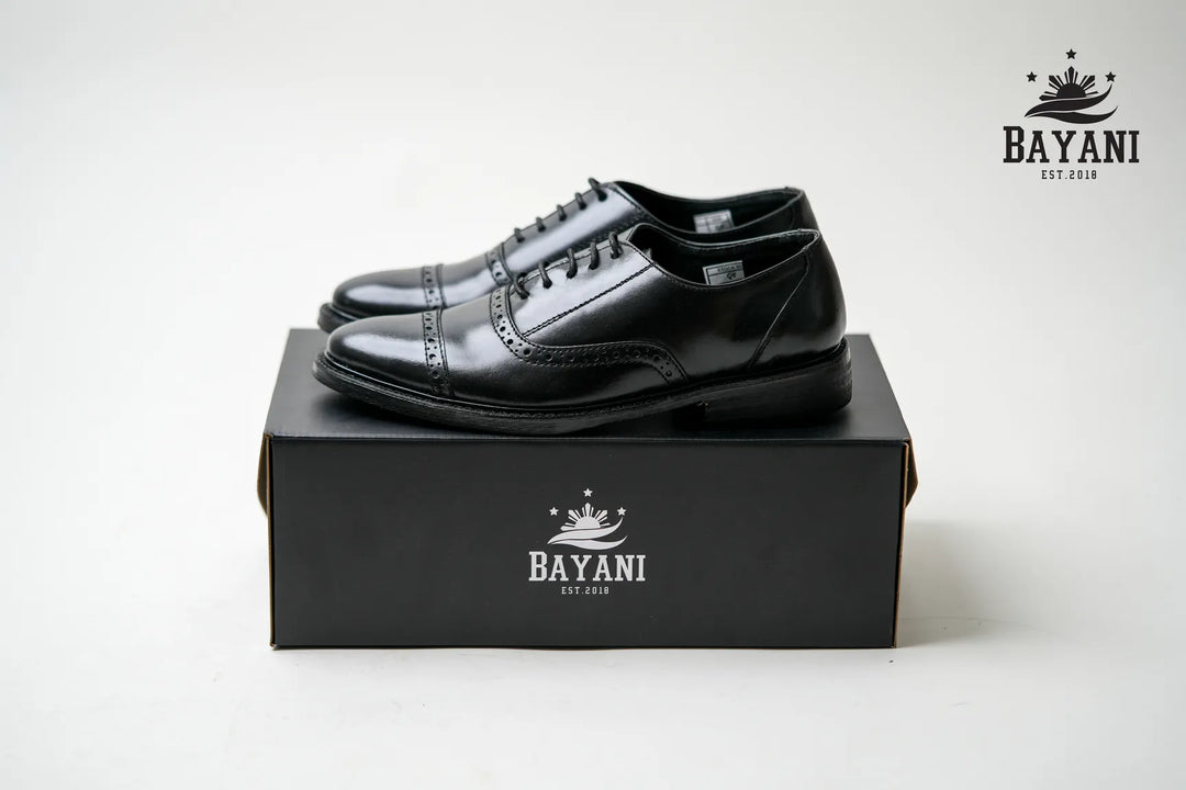 Black leather shoes on a black box with Bayani logo on a white background
