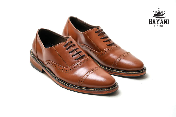 Pair of brown leather shoes with a white background and Bayani logo.
