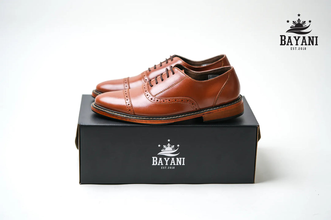 Brown leather shoes on a black Bayani box with the brand logo.

