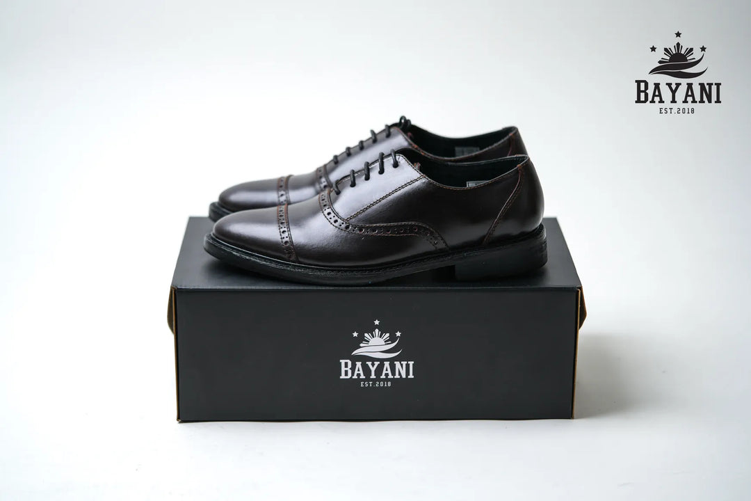 Black leather shoes on a Bayani branded box with a white background
