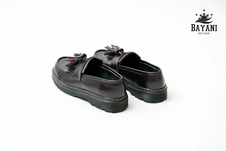 Black loafers with tassels on a white background, featuring the Bayani brand logo.
