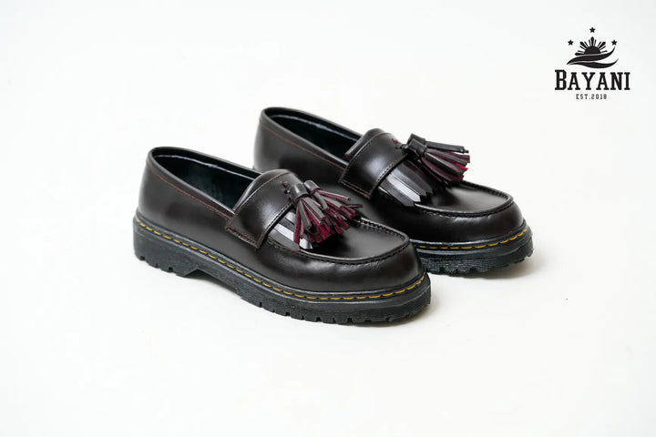 Pair of black loafers with tassels on a white background, featuring the Bayani brand logo.
