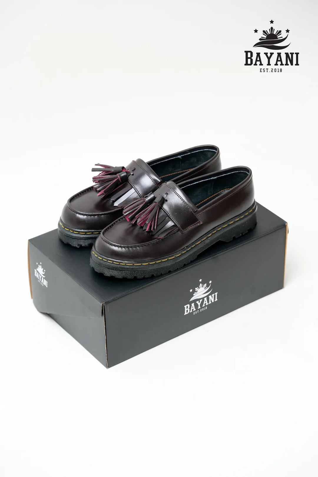 Pair of black loafers with tassels on a Bayani branded box.
