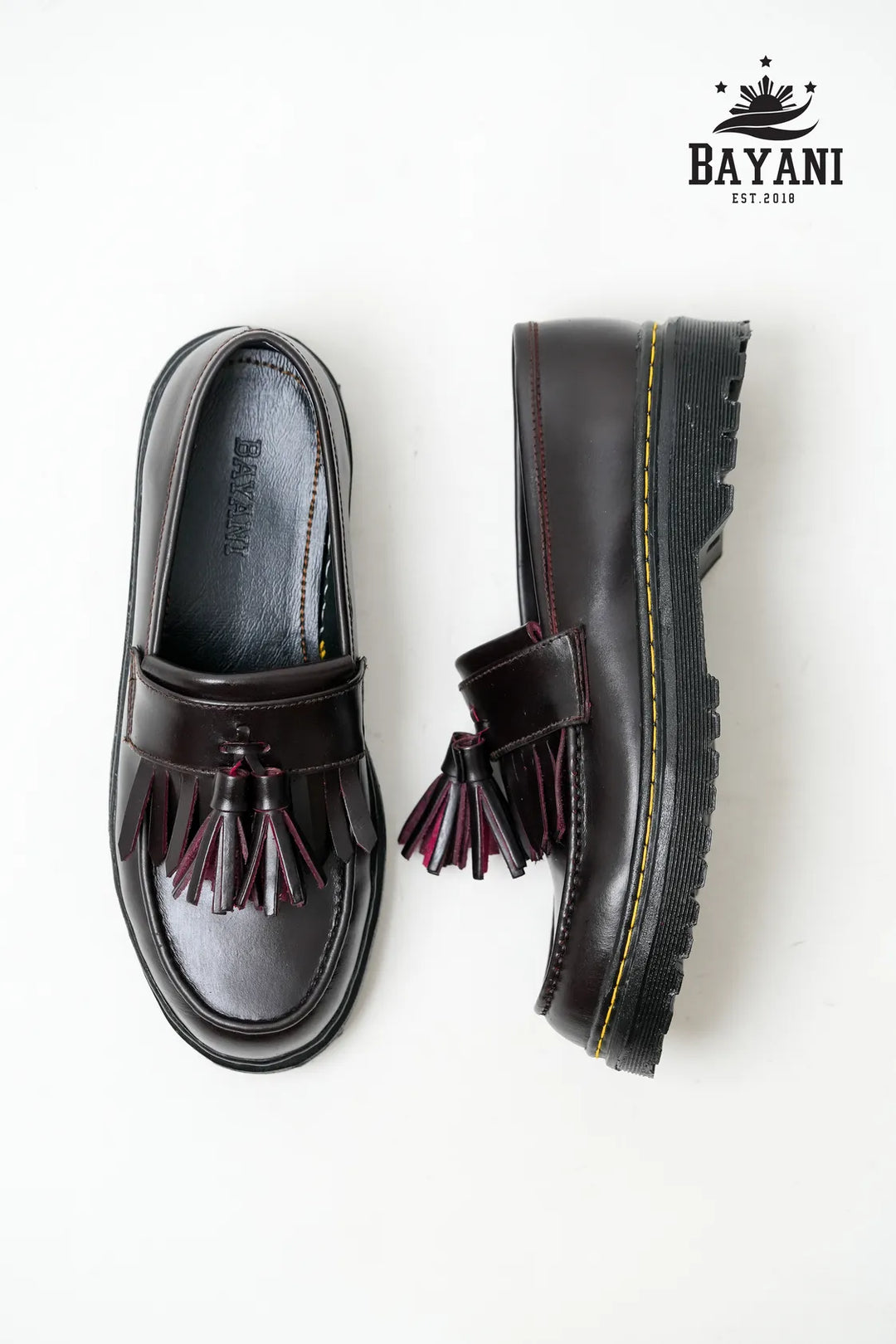 Black loafers with tassels on a white background, featuring the Bayani brand logo.
