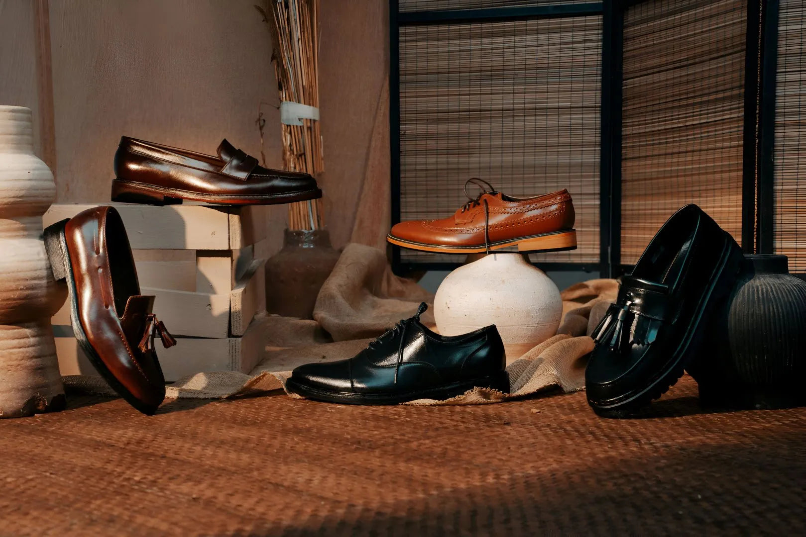 Five pairs of men's dress shoes displayed on a textured surface with decorative elements.