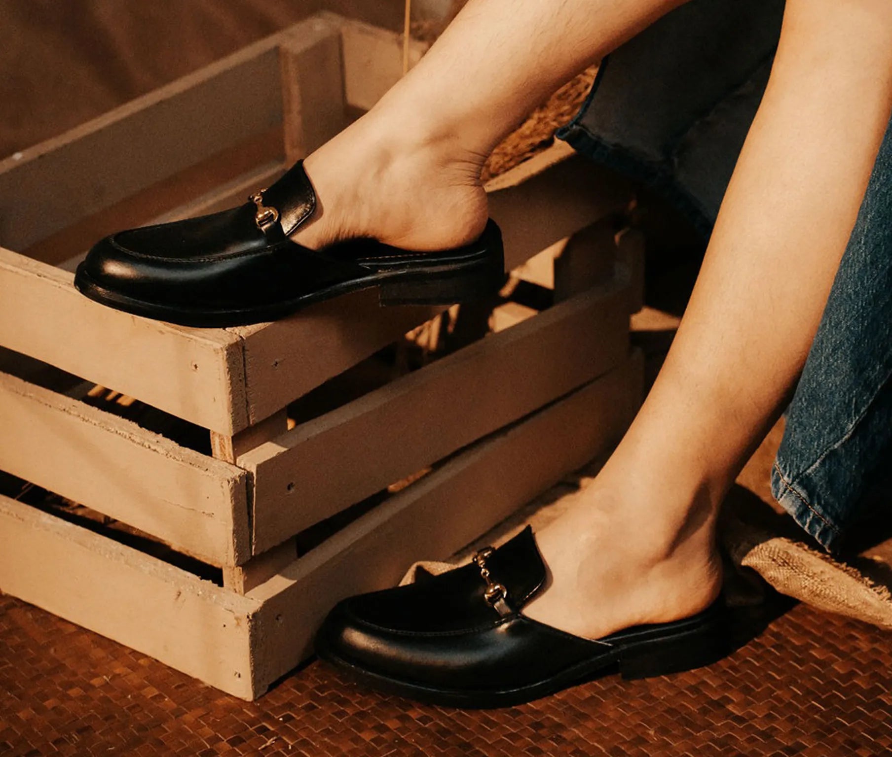 Person wearing black loafers stepping onto a wooden crate