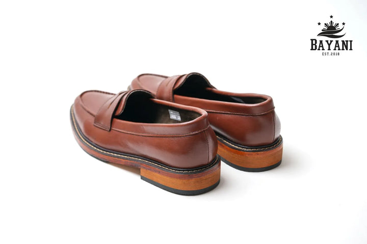 Brown loafers on a white background with Bayani logo.

