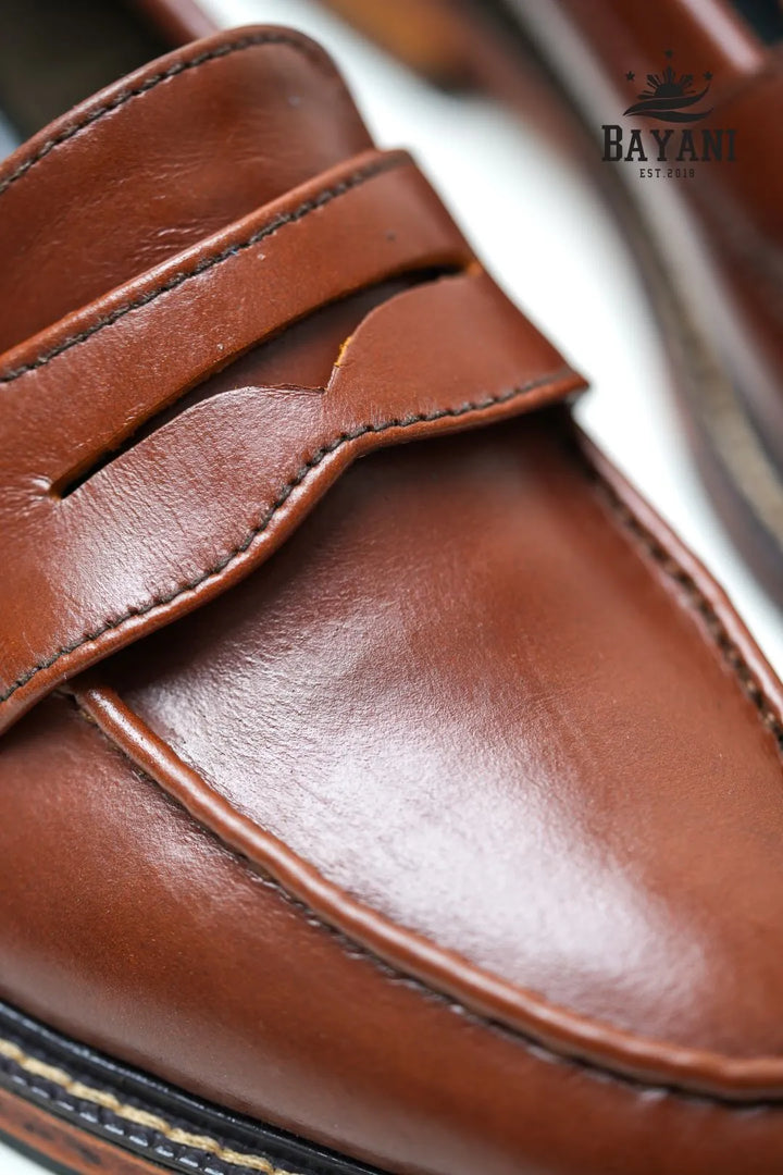 Close-up of a brown leather loafer with &