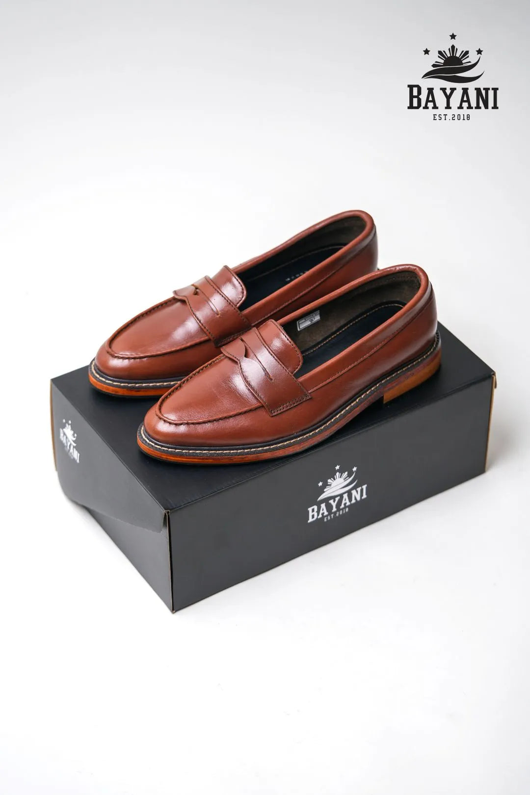 Brown loafers on a black box with Bayani logo on a white background

