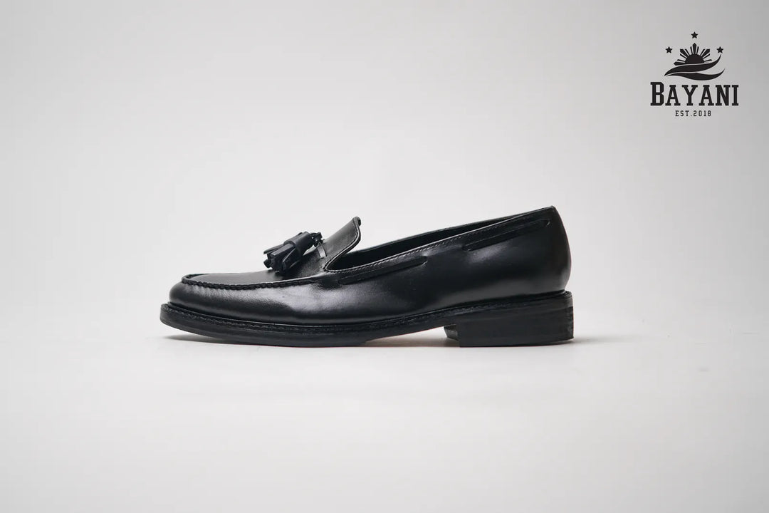 Black loafer shoe with a tassel on a light gray background, featuring the Bayani brand logo.
