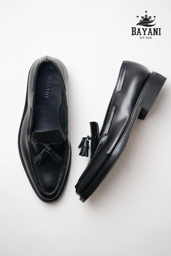 Black loafers with tassels on a white background, featuring the Bayani brand.
