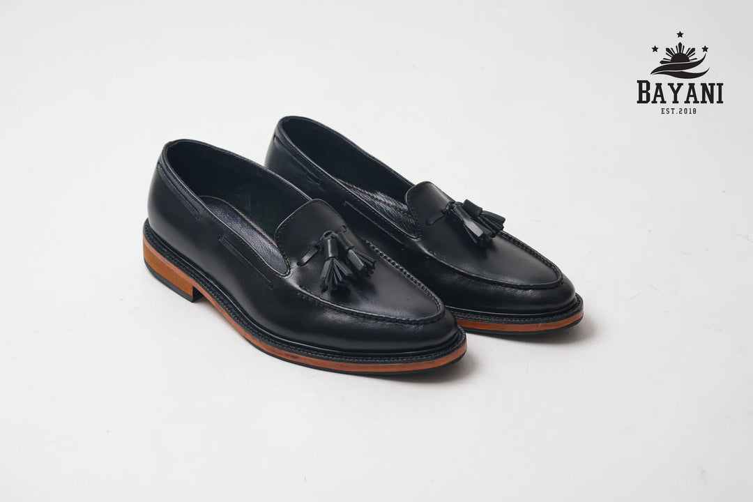 Black loafers with tassels on a white background, featuring the Bayani brand logo.
