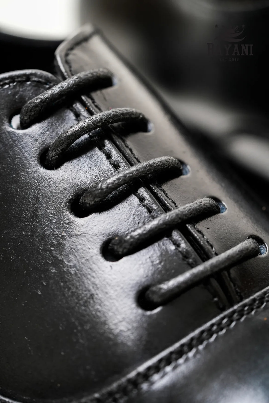 Close-up of a black leather shoe with laces, brand &