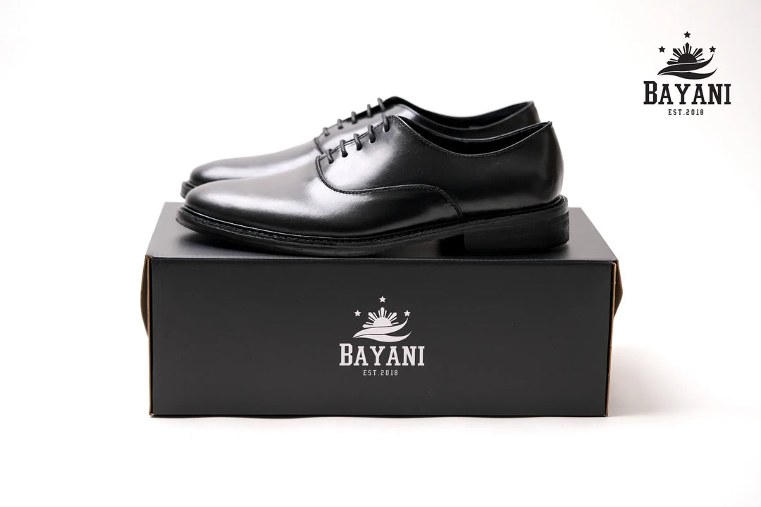 Black dress shoes on a black box with Bayani logo on a white background
