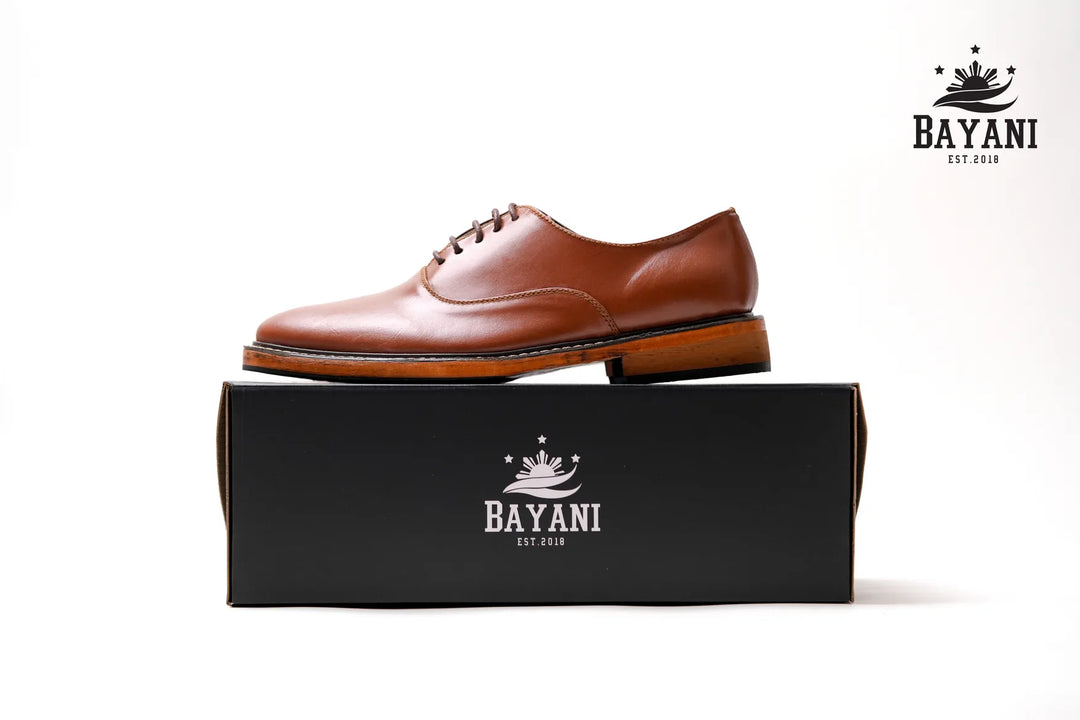Brown leather shoe on a black box with Bayani logo against a white background
