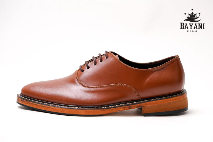 Brown leather shoe on a white background with Bayani logo.
