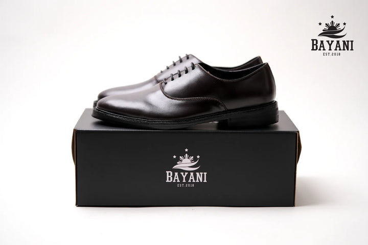 Black leather shoes on a black box with Bayani logo on a white background
