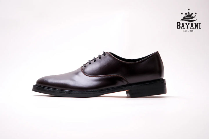 Brown leather shoe on a white background with Bayani logo.
