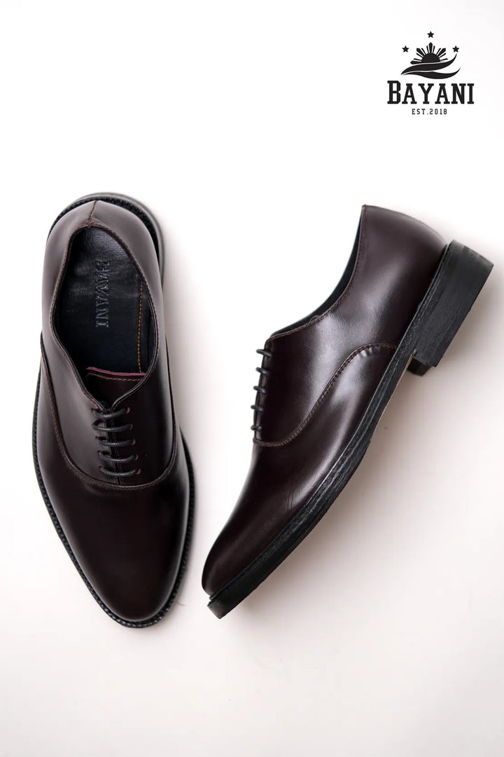 Brown dress shoes on a white background with Bayani logo.
