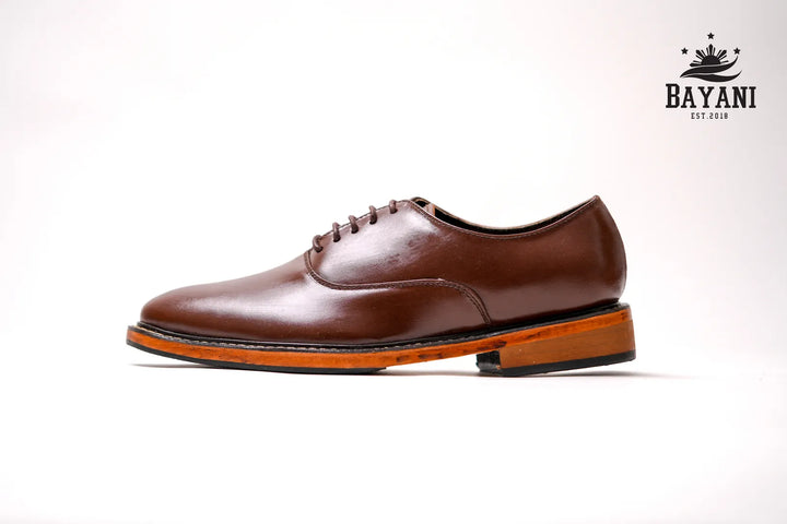 Brown leather shoe on a white background with Bayani logo.
