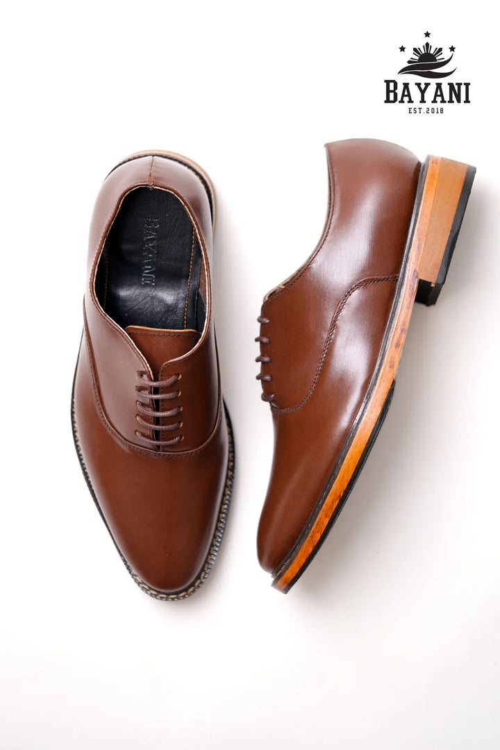 Pair of brown leather shoes with a white background and Bayani logo.
