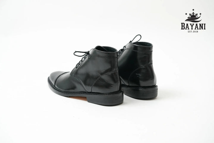 Black leather boots on a white background with Bayani logo.

