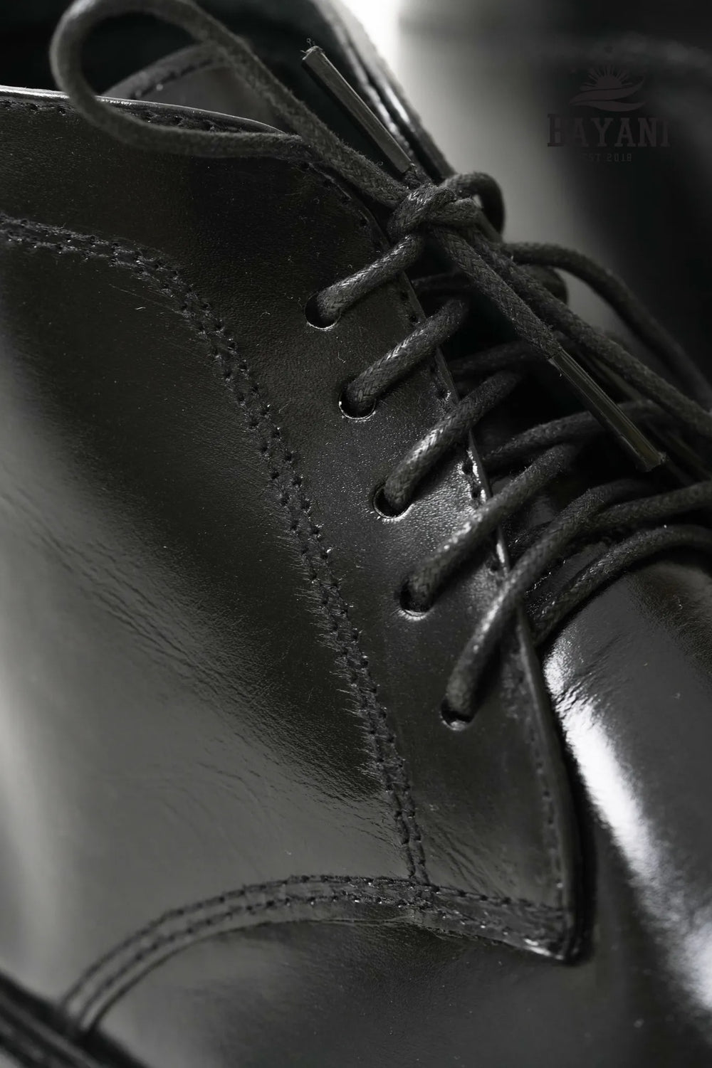 Close-up of a black leather shoe with laces, brand 'BAYANI' visible.

#color_black