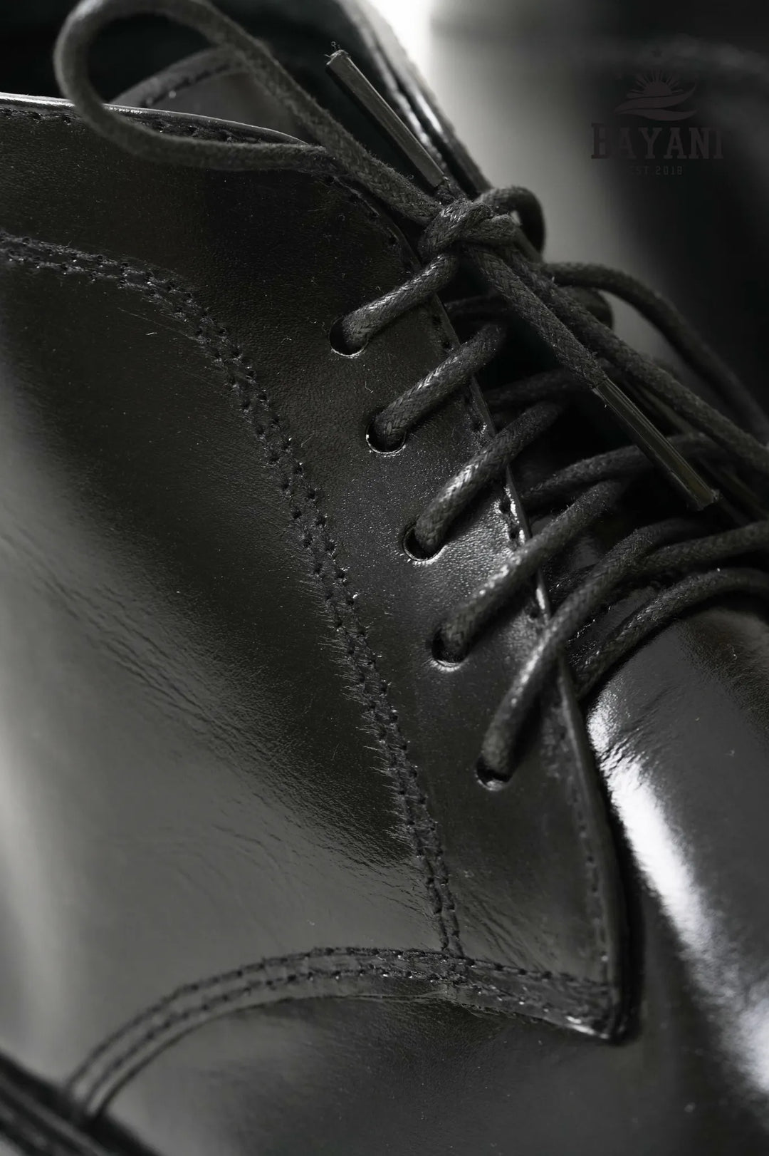 Close-up of a black leather shoe with laces, brand &