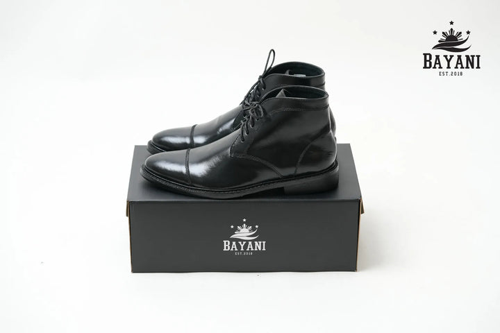 Black leather boots on a black box with Bayani logo on a white background

