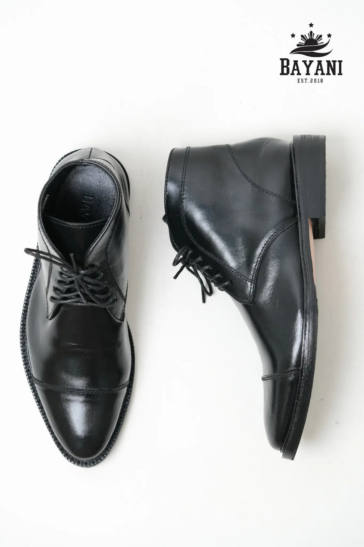 Pair of black leather shoes on a white background with Bayani logo.

