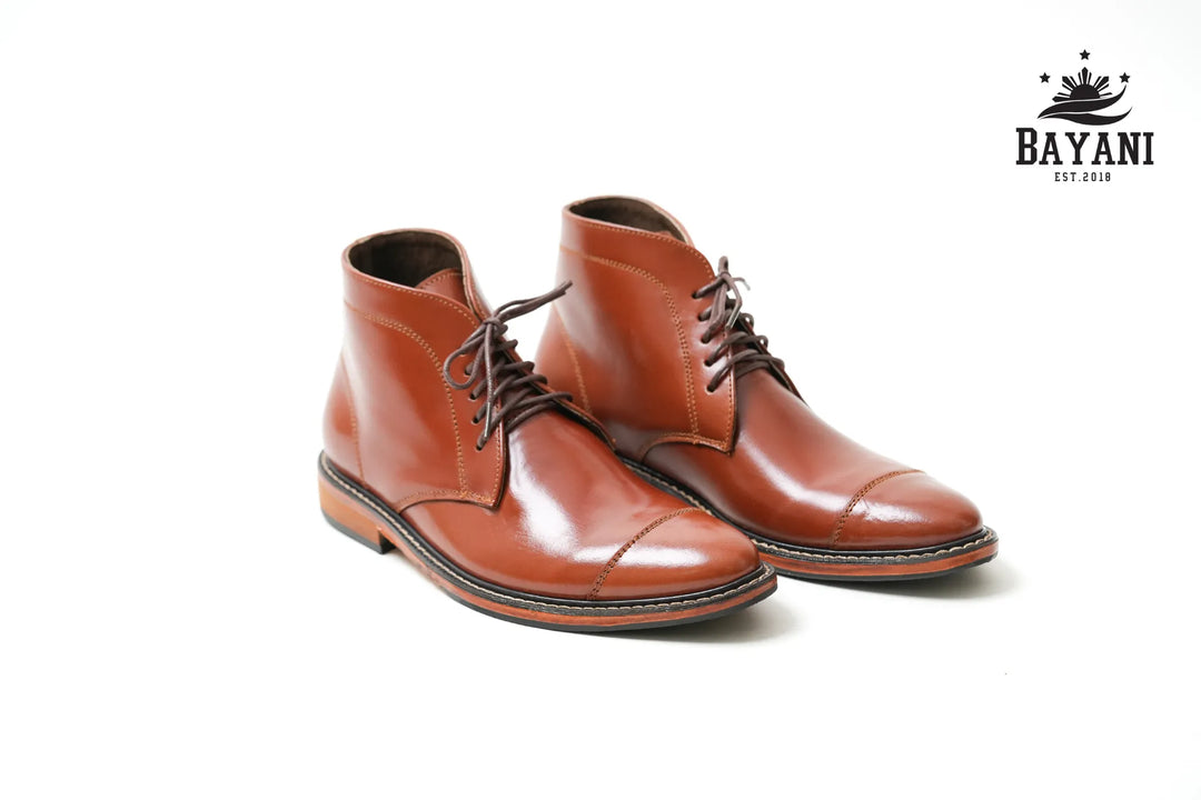 Pair of brown leather boots on a white background with Bayani logo.
