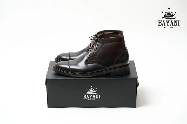 Brown leather boots on a black box with Bayani logo on a white background
