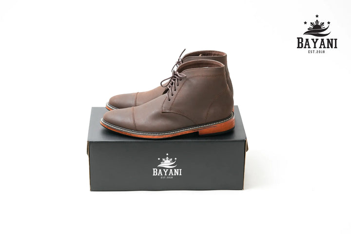 Brown leather boots on a Bayani branded box with the Bayani logo.
