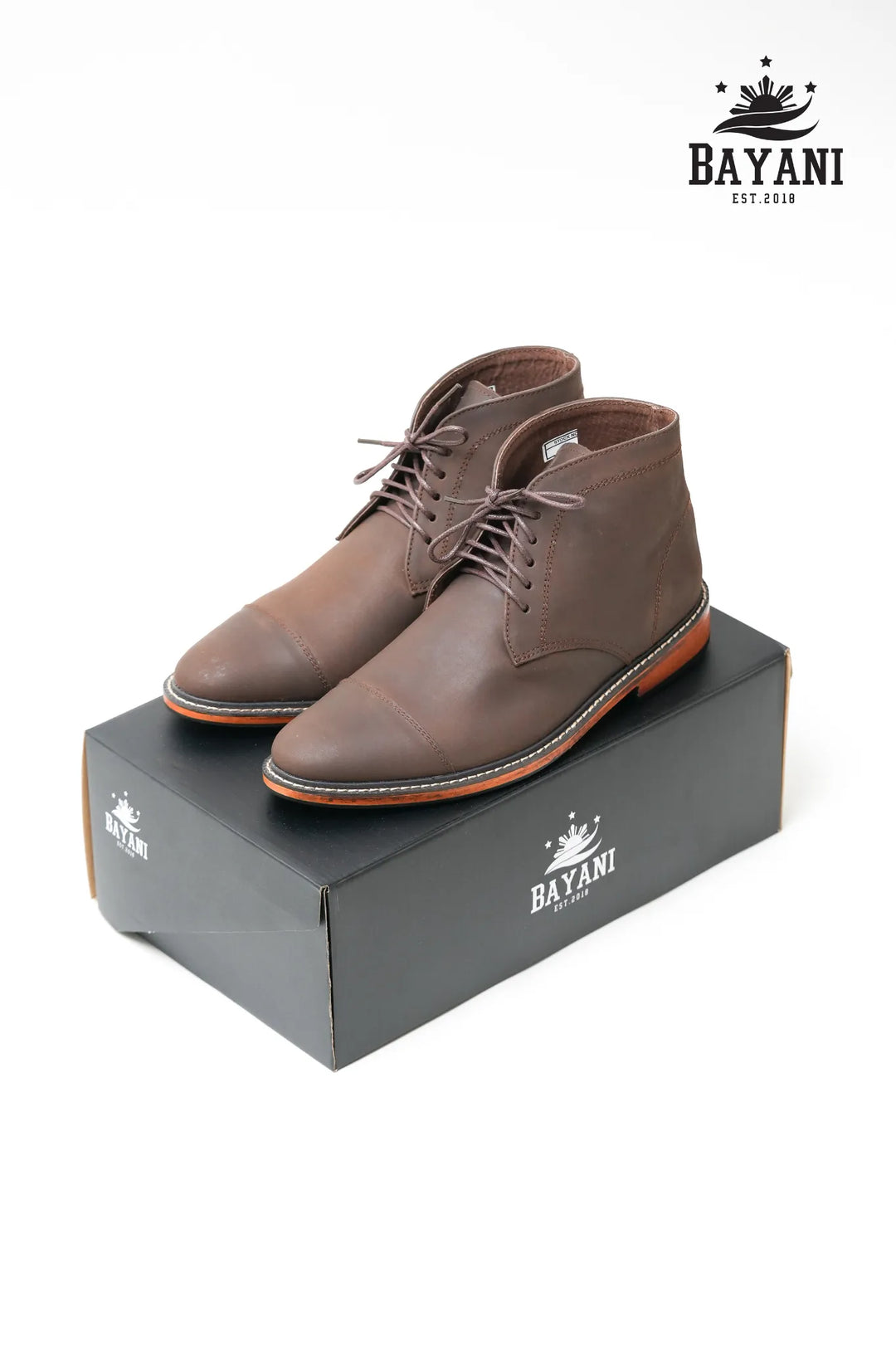 Brown leather boots on a Bayani branded box with the Bayani logo above.
