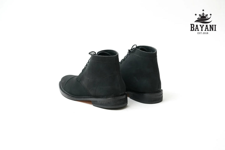 Black boots on a white background with Bayani logo.
