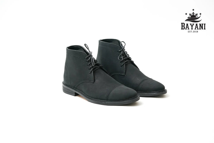 Pair of black leather boots on a white background with Bayani logo.
