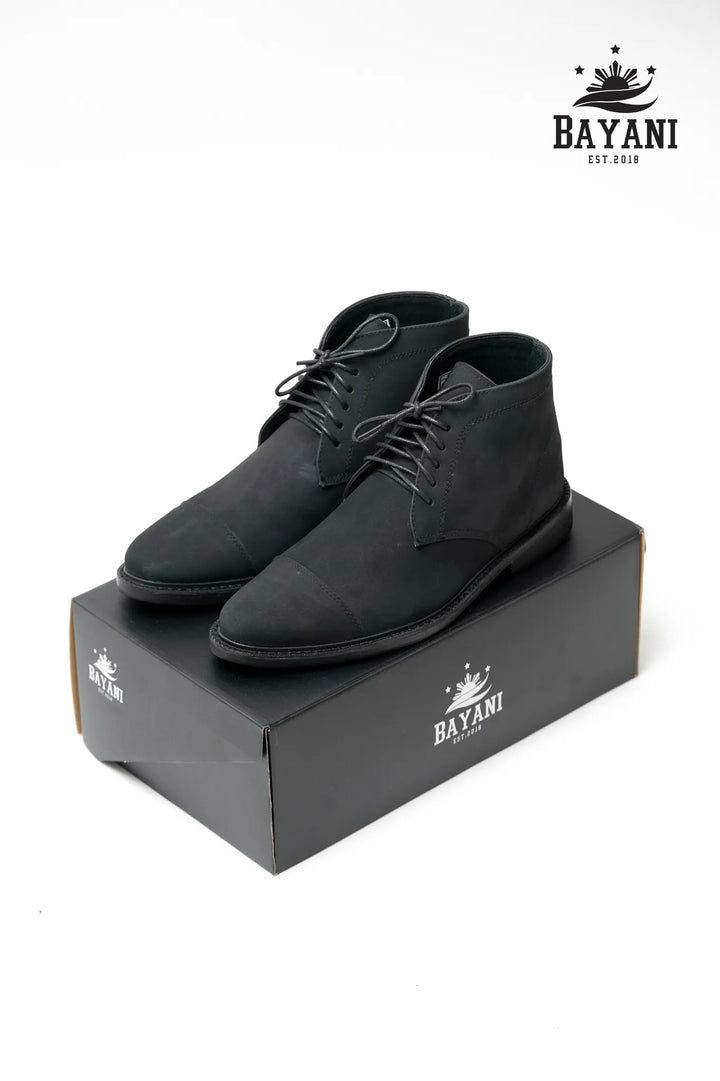 Black suede shoes on a black box with Bayani logo above, on a white background
