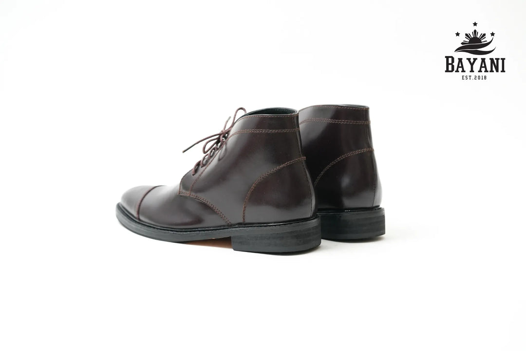 Pair of brown leather boots on a white background with Bayani logo.

