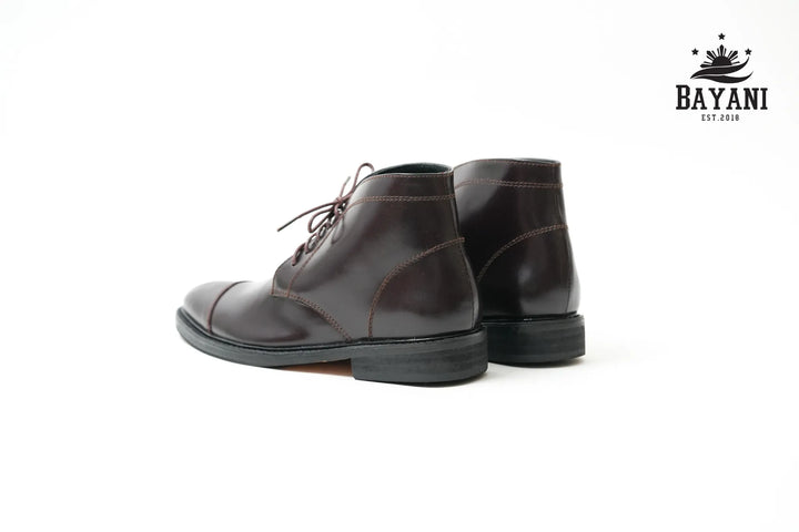 Pair of brown leather boots on a white background with Bayani logo.

