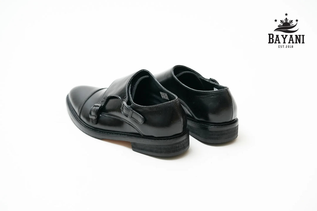 Pair of black shoes on a white background with Bayani logo.

