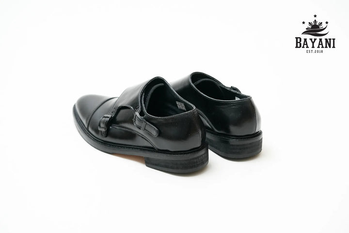Pair of black shoes on a white background with Bayani logo.
