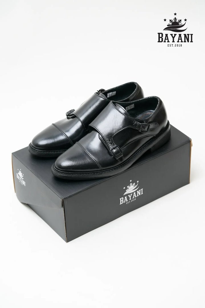 Black dress shoes on a Bayani branded box with the Bayani logo above.

