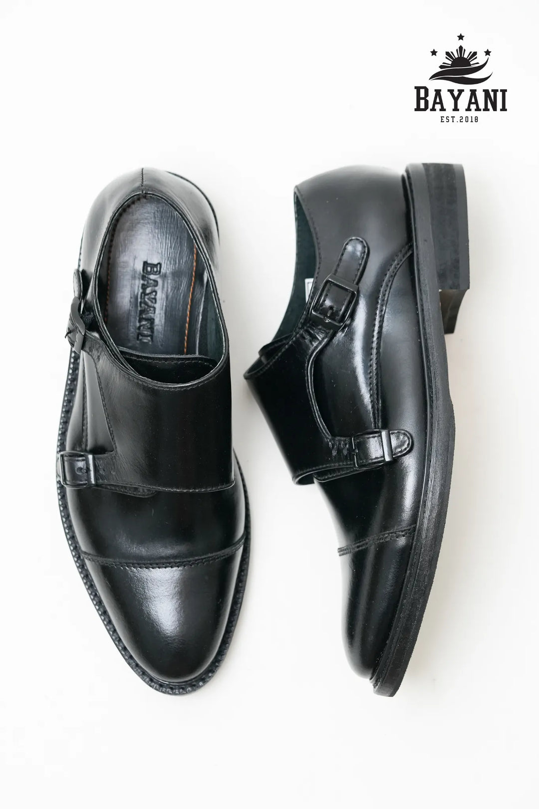 Black leather shoes with buckles on a white background, featuring the Bayani brand.
