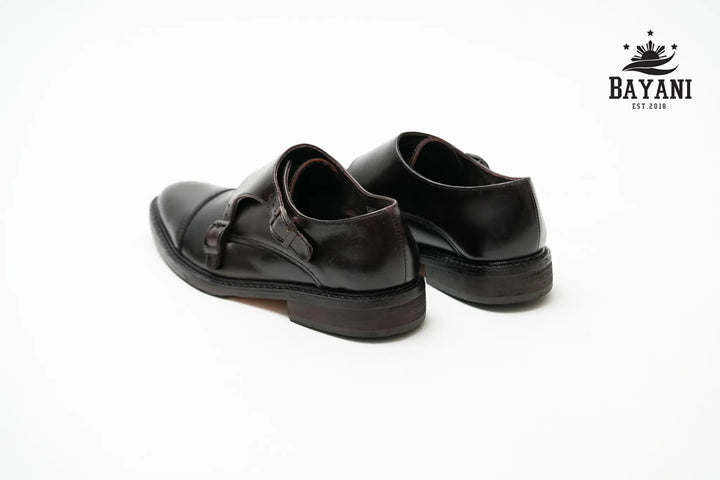 Pair of black leather shoes on a white background with Bayani logo.
