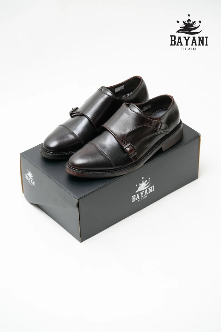 Pair of black leather shoes on a Bayani branded box with the Bayani logo above.
