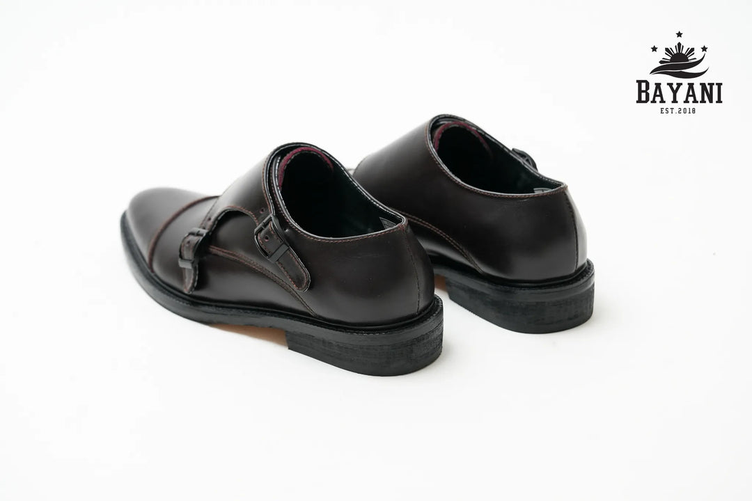 Pair of black leather shoes on a white background with Bayani logo.
