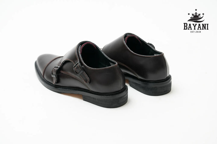 Pair of black leather shoes on a white background with Bayani logo.
