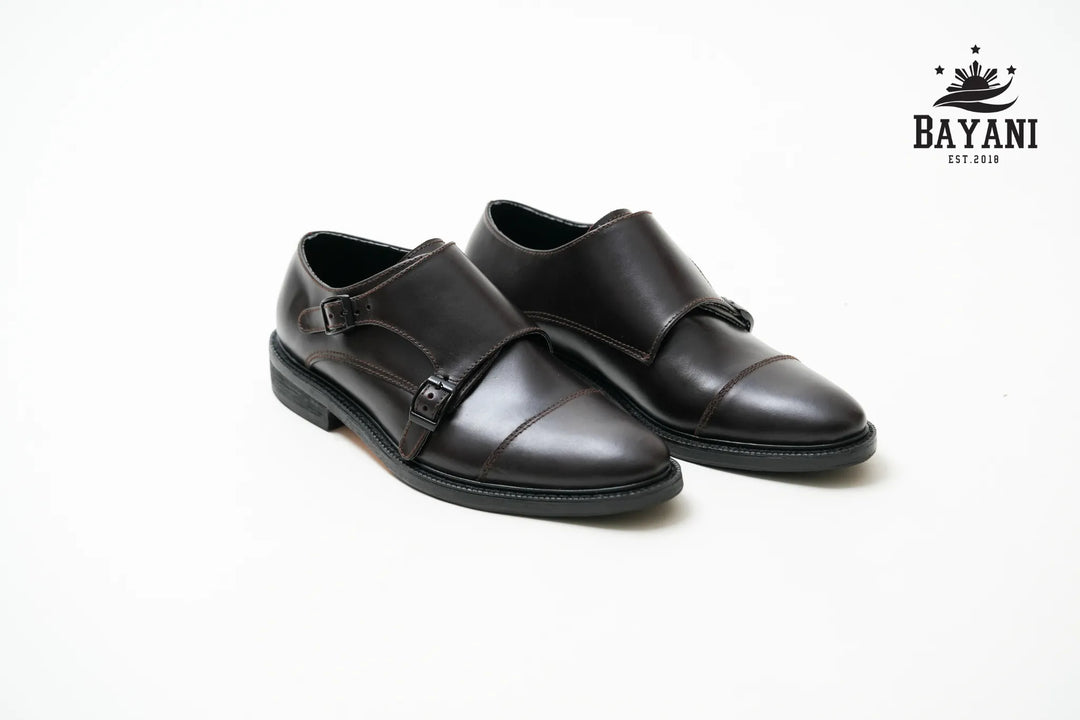 Pair of black leather shoes on a white background with Bayani logo.

